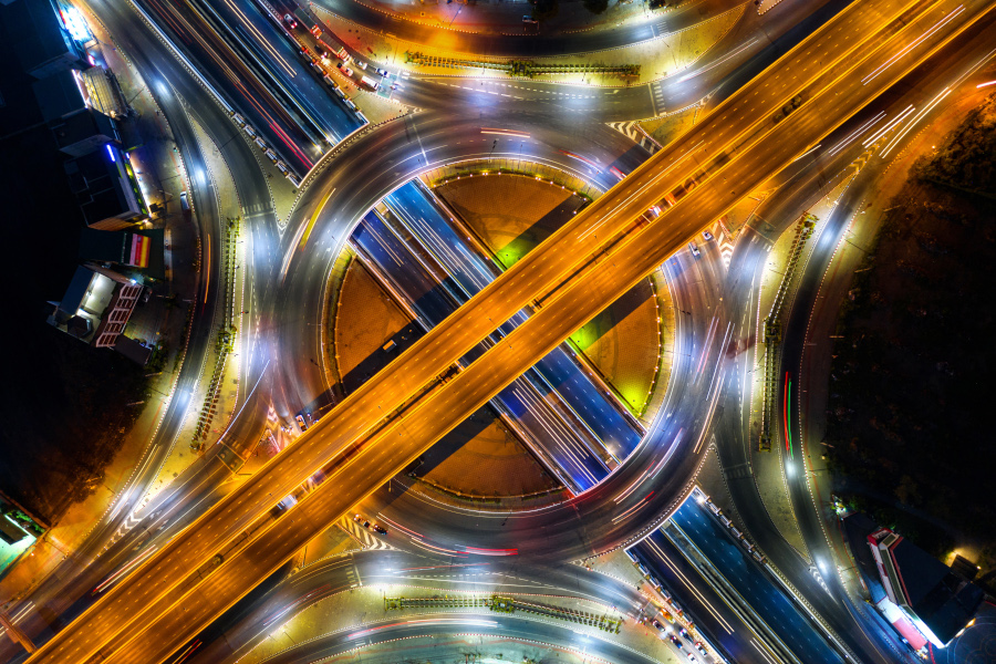 Aerial view of traffic in roundabout and highway at night.